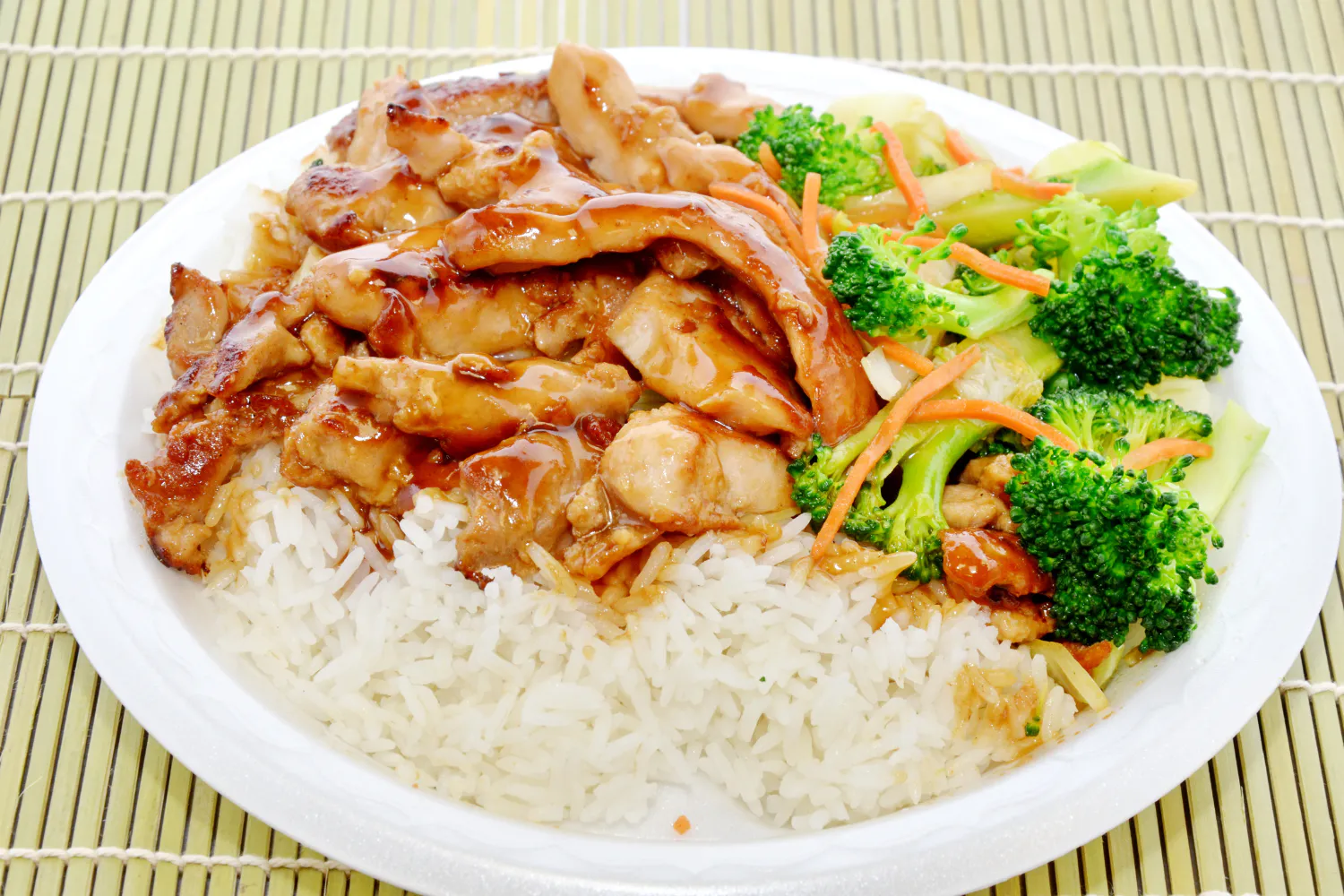 Glazed teriyaki chicken over white rice with broccoli and carrot strips